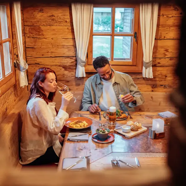Stroblhaus Ein Mann und eine Frau sitzen an einem Tisch mit Essen und Getränken.