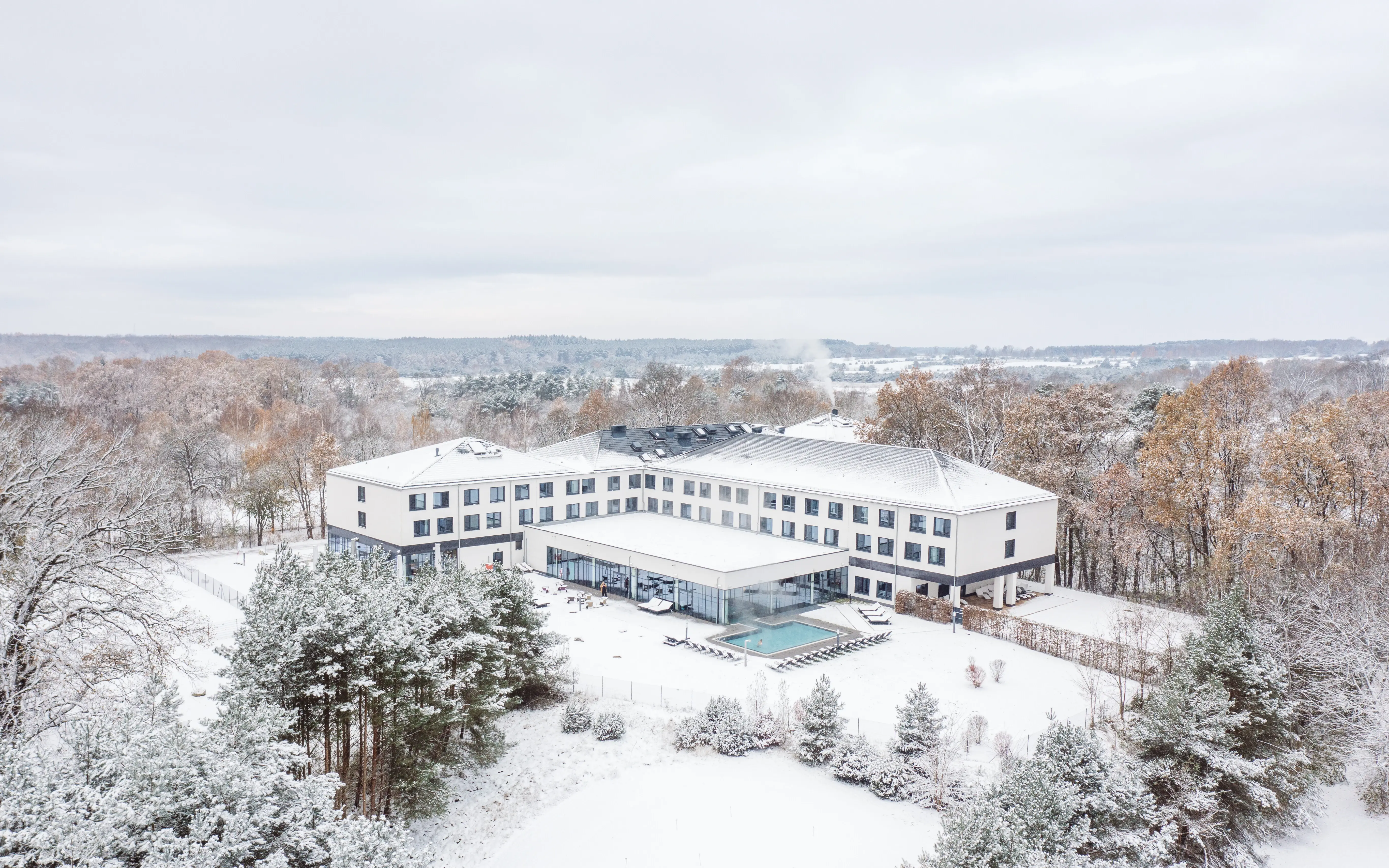 aja Bad Saarow im Winter Ein Gebäude mit einem Pool in der Mitte, umgeben von Schnee.