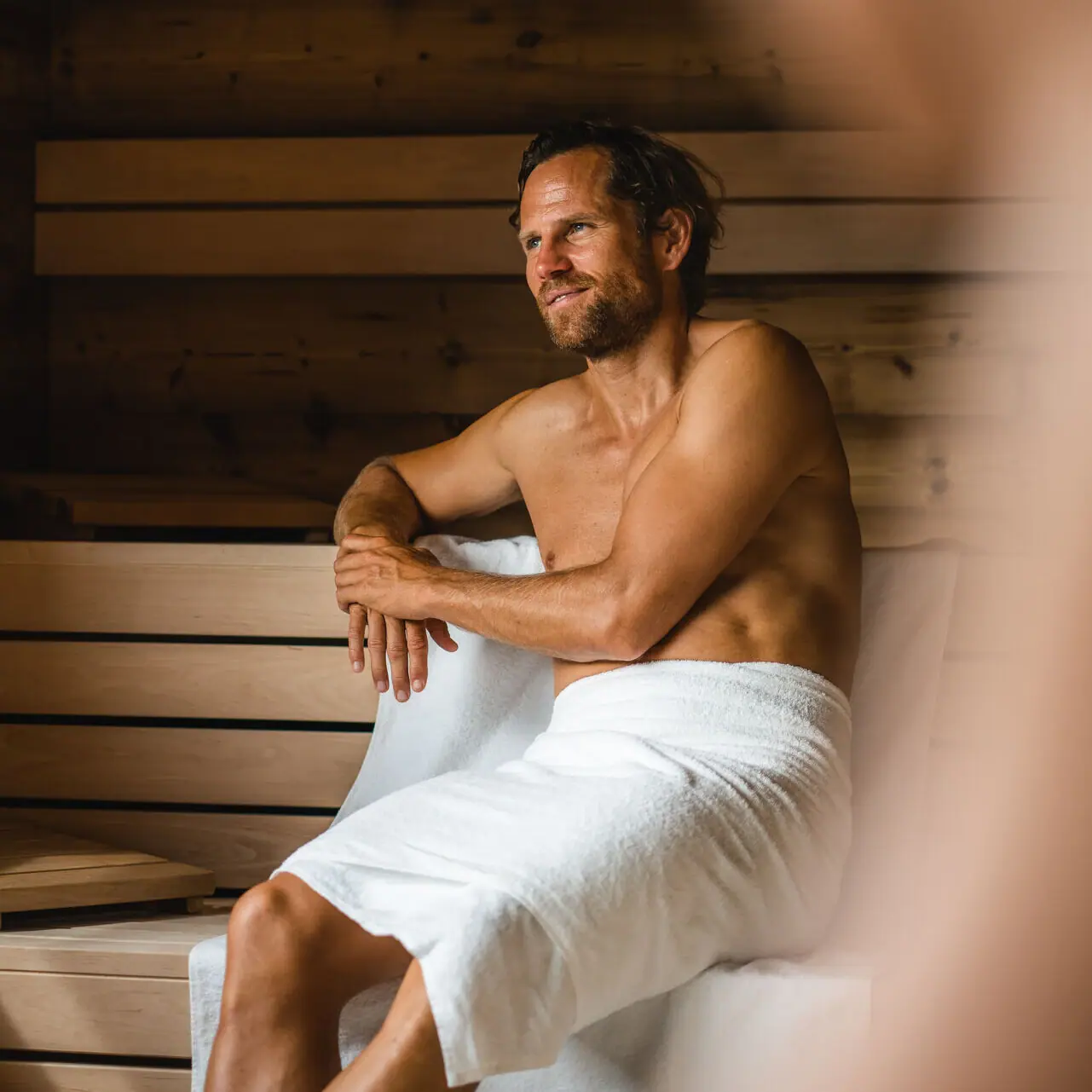 Sauna aja Garmisch Ein Mann sitzt in der Sauna vom aja Garmisch-Partenkirchen mit einem Handtuch.