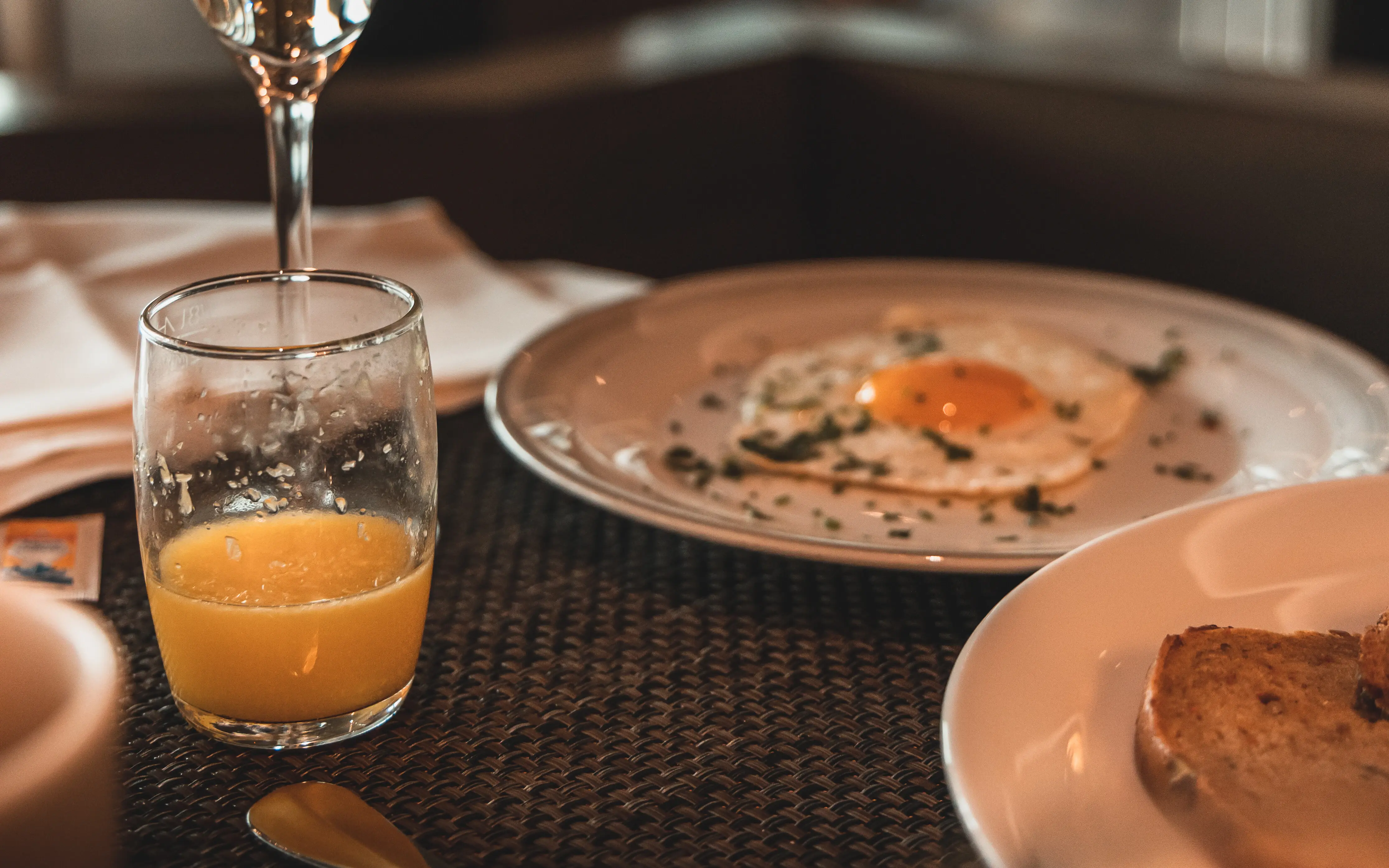 Spiegelei Ein Glas Champagner neben Tellern mit Essen.