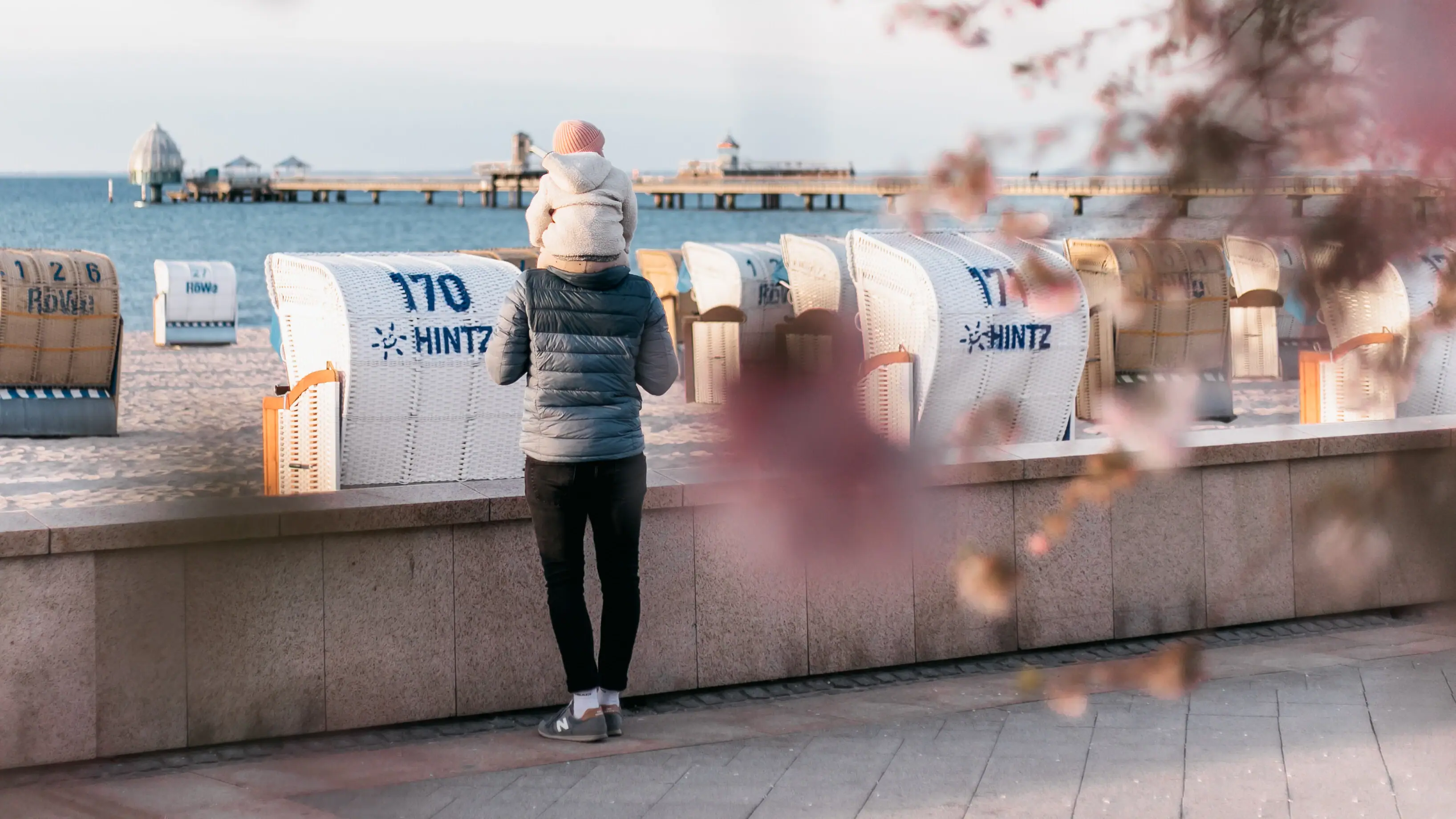 Promenade Grömitz Ein Mann steht auf einer Promenade mit einem Baby auf ihren Schultern.