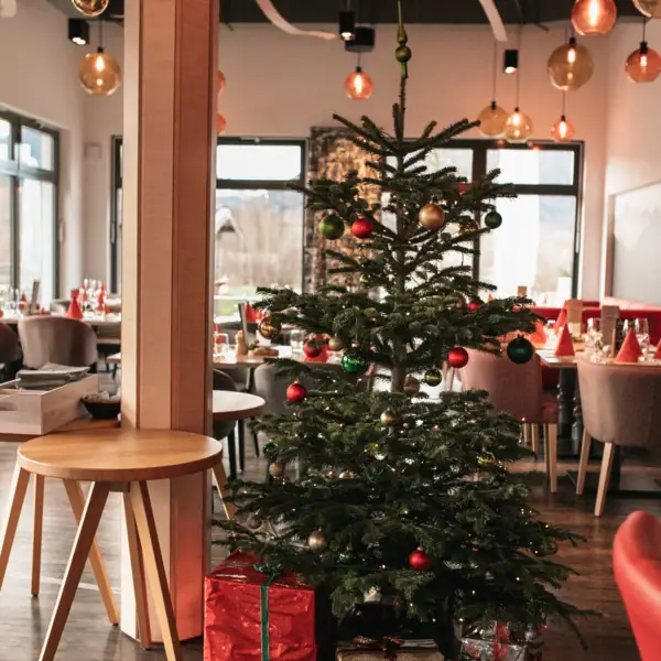 Tannenbaum Ein Weihnachtsbaum in einem Raum mit Tischen und Stühlen.