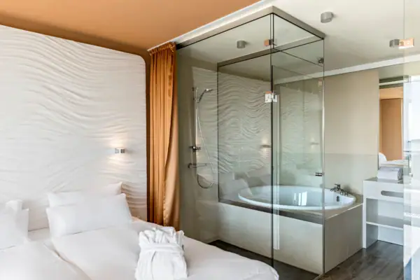Suite im aja Warnemünde Badezimmer mit Glasdusche und Bett