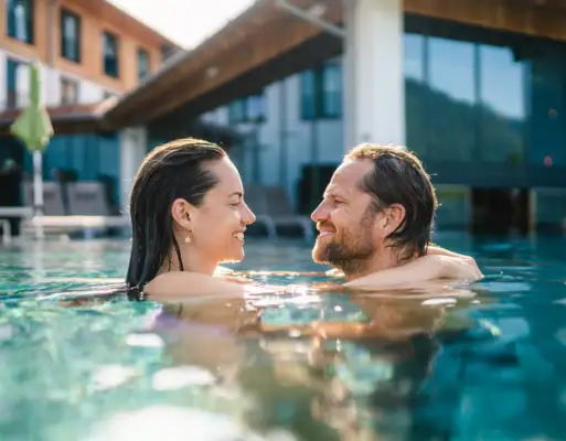 Wellness Ein Mann und eine Frau im Schwimmbecken vor einem Hotel..