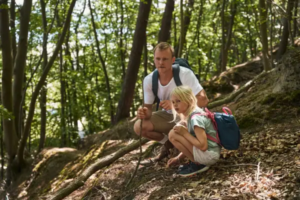 Wald Ein Mann und ein Mädchen sitzen auf einem Hügel im Wald.