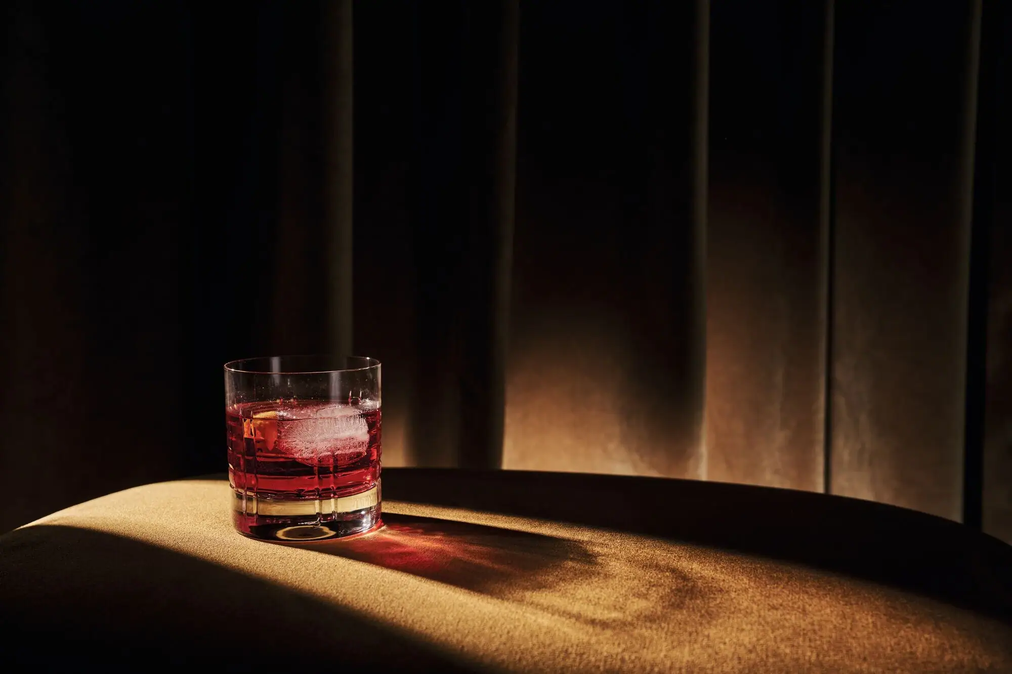 Stork Club Schlepzig Ein Glas mit roter Flüssigkeit und Eis auf einem Tisch.