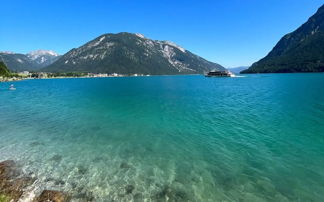 Blick auf den blauen Achensee mit Bergen im Hintergrund.