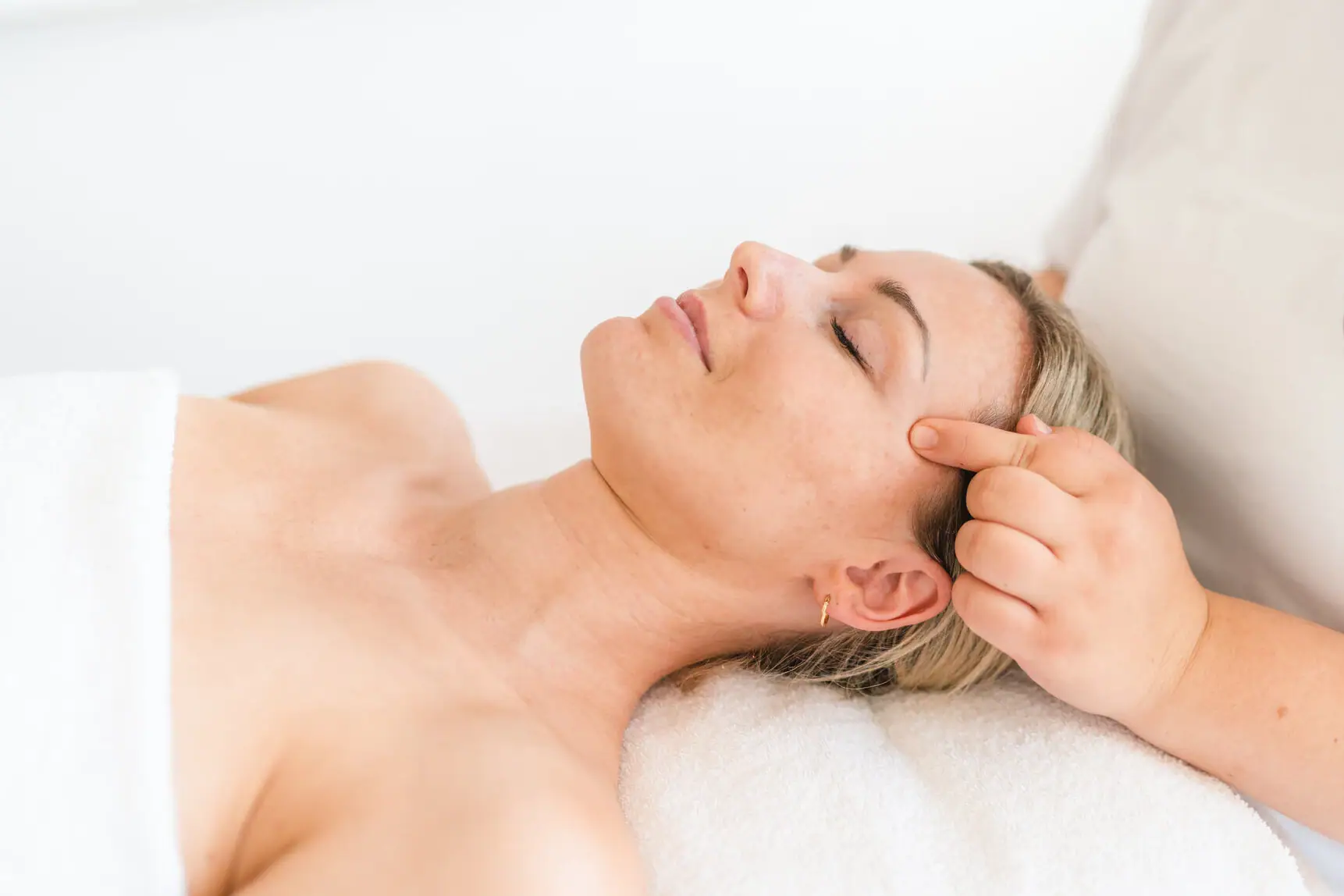 Anwendung im aja Warnemünde Frau liegt auf einem Massagetisch.