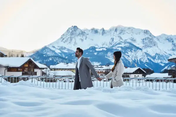 Schnee in Werfenweng Ein Mann und eine Frau halten sich im Schnee an den Händen.