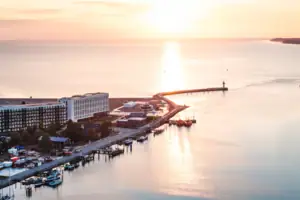 aja Travemünde Das aja Travemünde direkt am Wasser gelegen mit einem Leuchtturm im Hintergrund.
