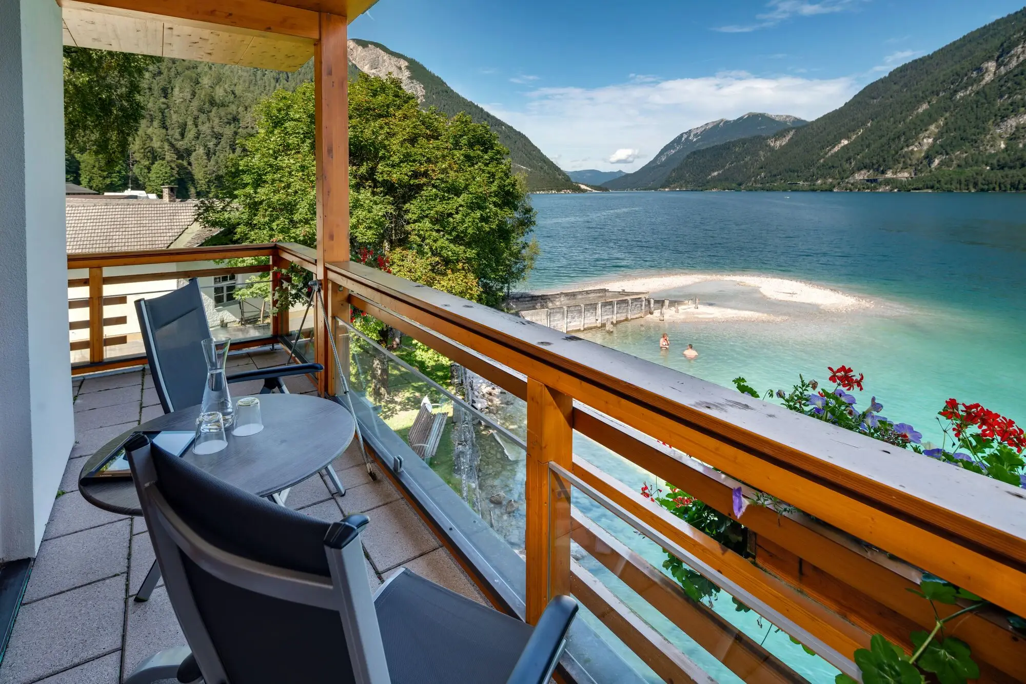 Balkon Fürstenhaus am Achensee Ein Balkon mit Tisch und Stühlen, der auf ein Gewässer blickt.