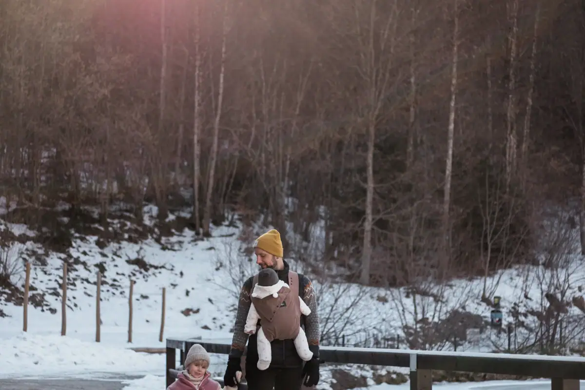 Familie im Winterurlaub Ein Mann und ein Kind gehen im Schnee über eine Brücke.