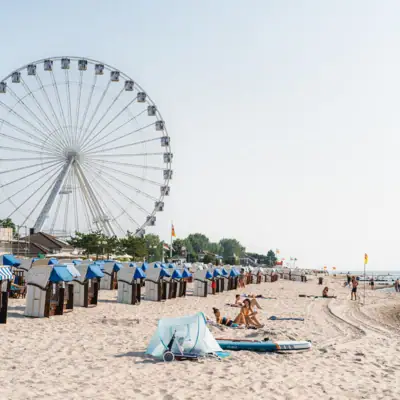 Aktivitäten in Grömitz Ein Strand mit einem Riesenrad und Menschen darauf.