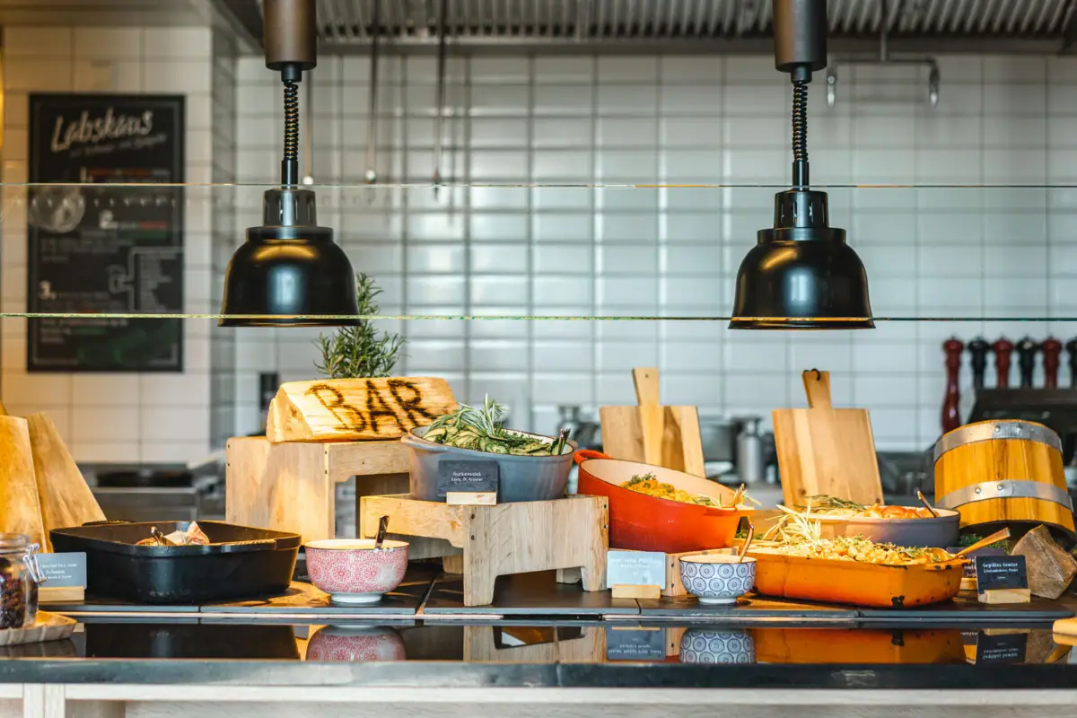 Restaurant im aja Warnemünde Buffet mit Schüsseln voller warmer Speisen.