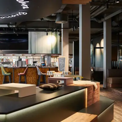 Barbereich im aja Ruhpolding Eine Bar mit Fernseher und Barhockern.