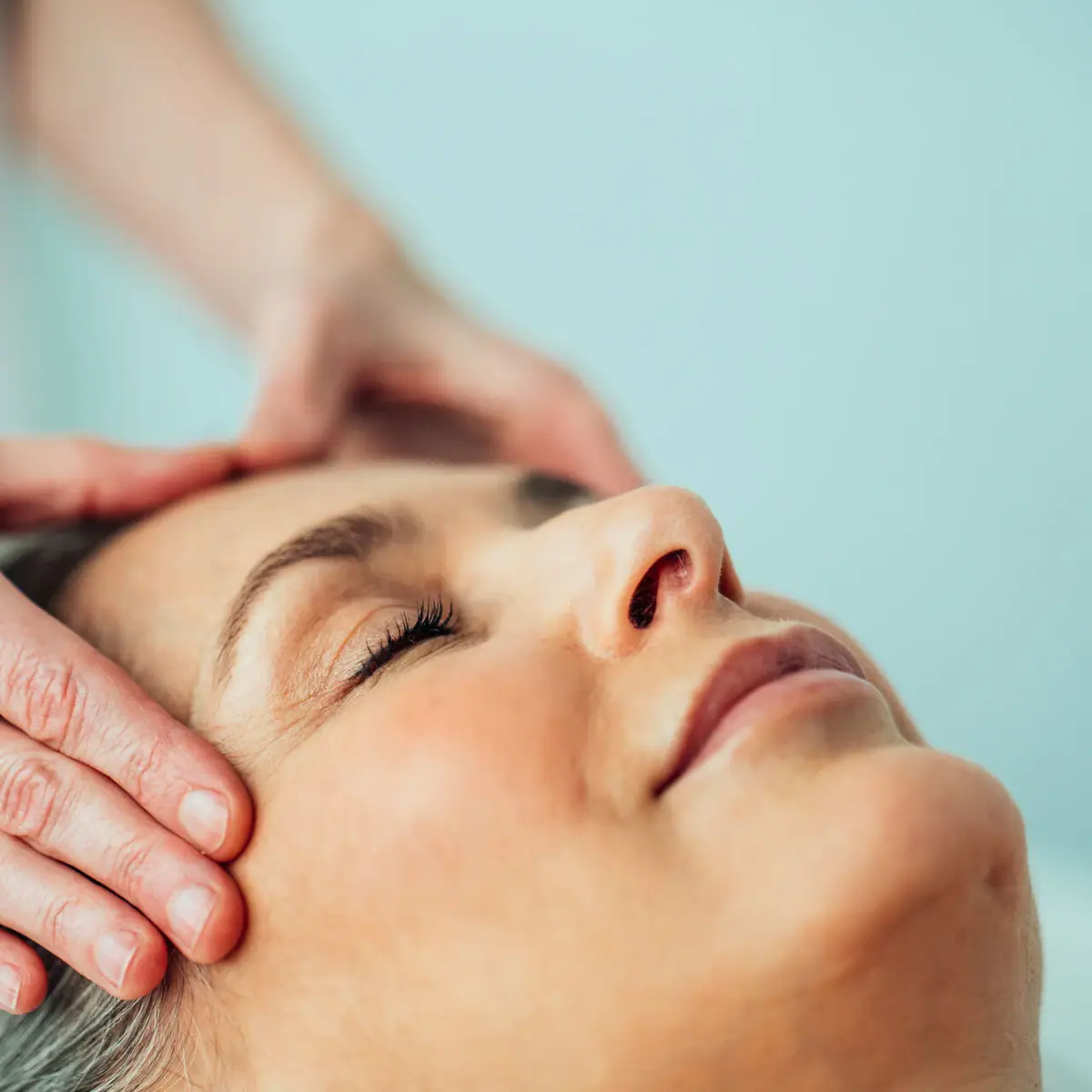 Kopfmassage Eine Person massiert den Kopf einer Frau.