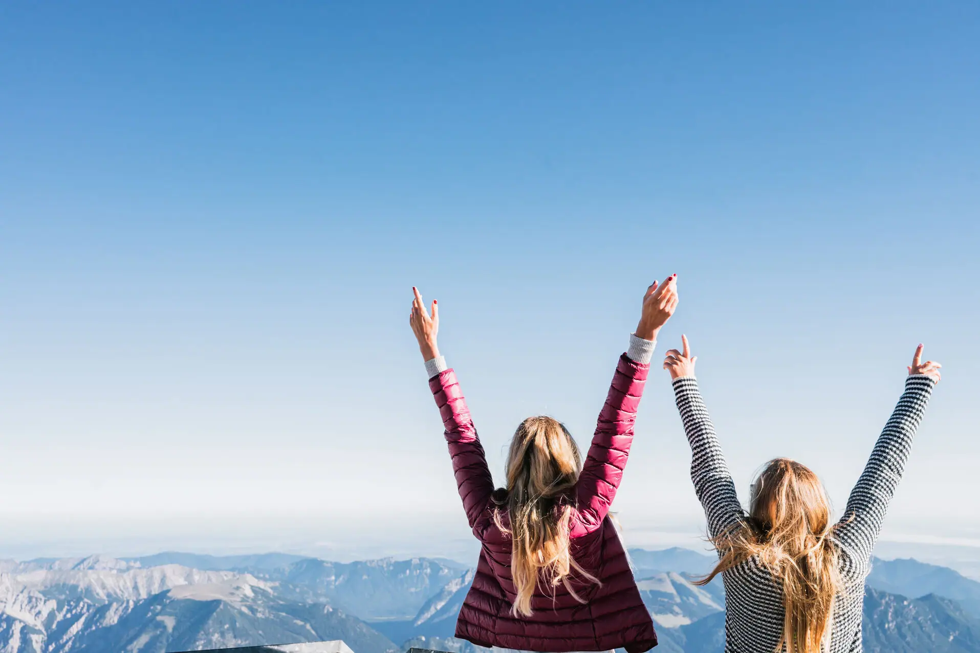 Zugspitze Zwei Frauen stehen auf einem Berg mit erhobenen Armen.