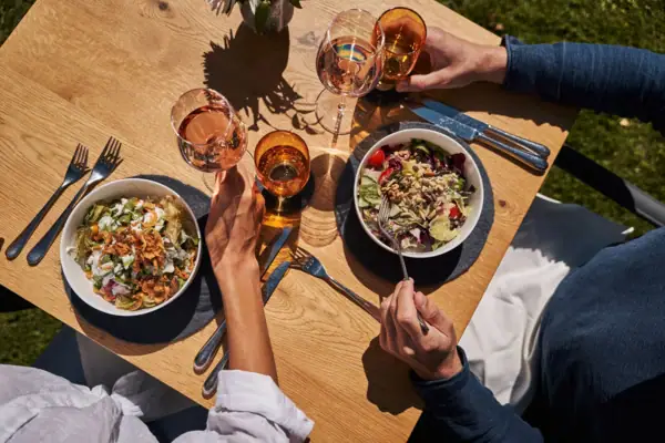 Gastgarten Eine Gruppe von Menschen isst an einem Tisch mit Essen und Getränken.
