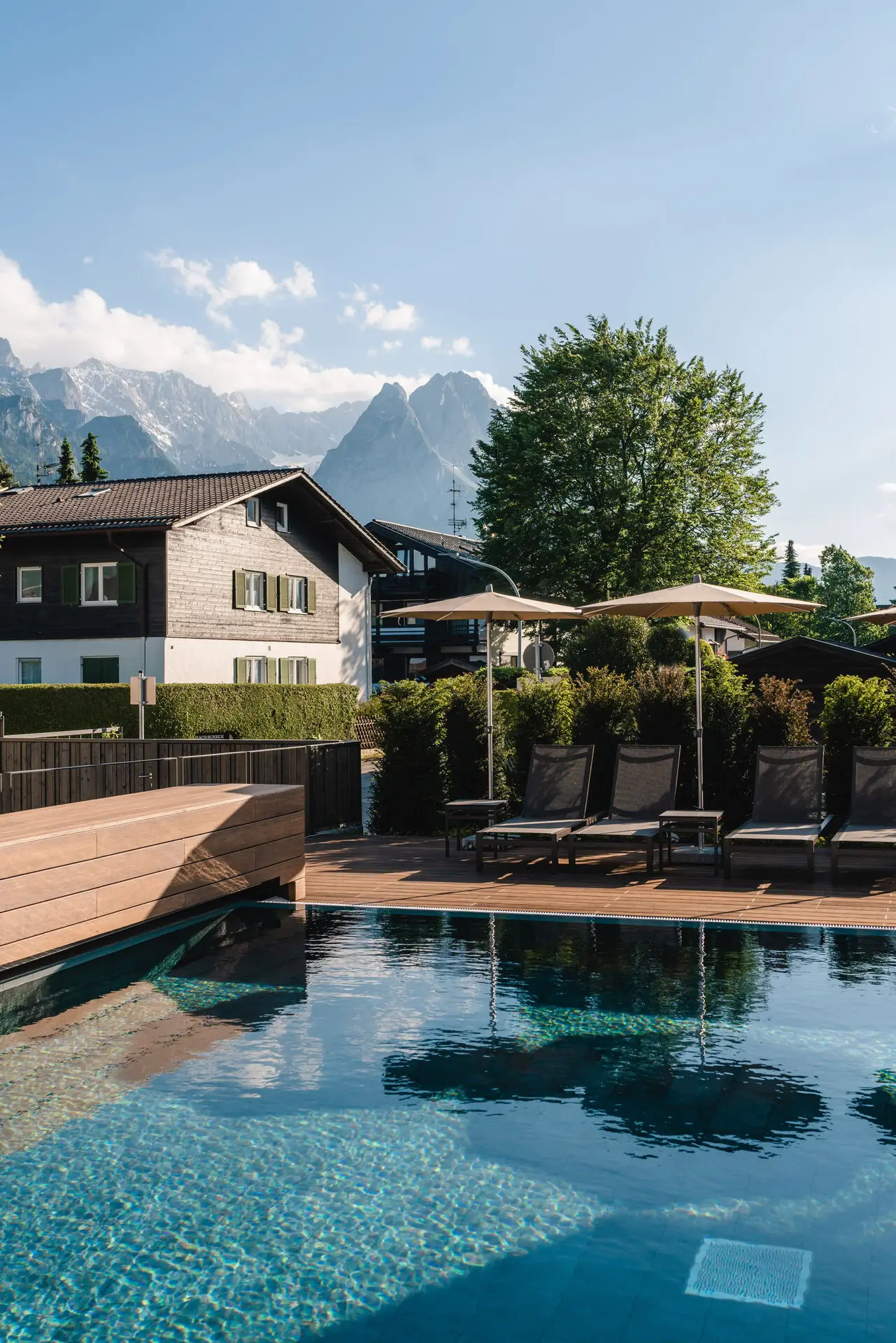 Außenpool Garmisch-Partenkirchen Pool mit Stühlen und Sonnenschirmen neben einem Haus