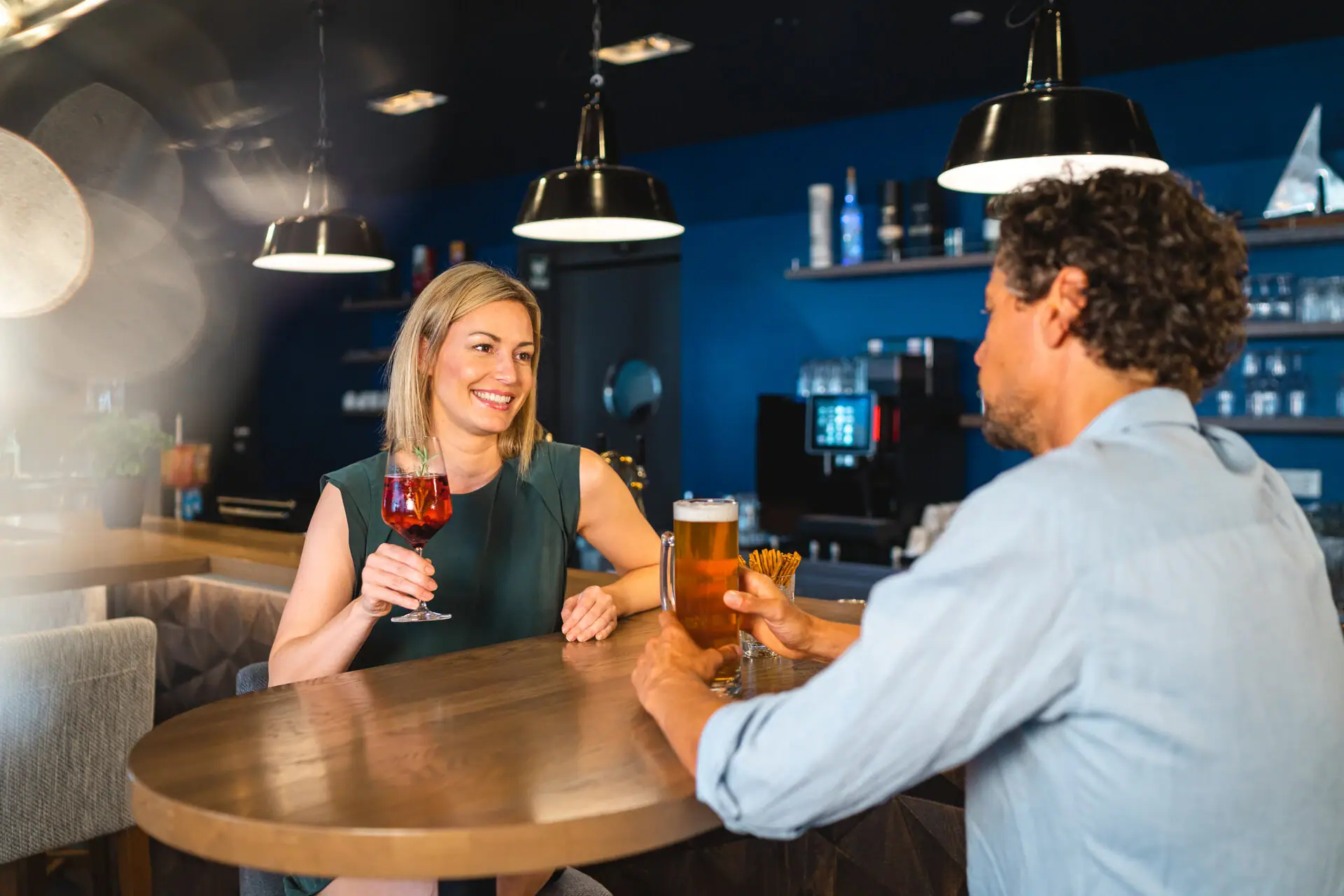aja Bar im aja Warnemünde Ein Mann und eine Frau sitzen an einem Tisch mit Getränken.