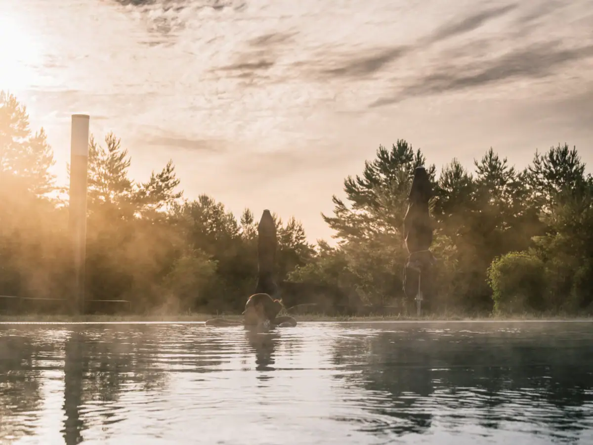 Außenpool Eine Frau schwimmt in einem Außenpool mit Bäumen und bewölktem Himmel.