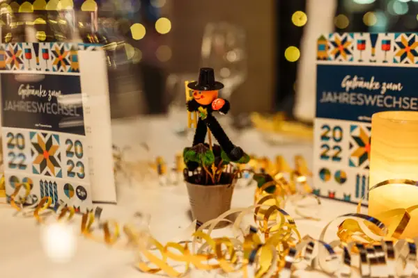 Silvester im aja Travemünde Dekoration bestehende aus einem Schornsteinfeger, Luftschlangen und weißer Tischdecke im Restaurant