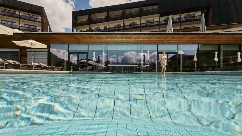 Schwimmbecken mit dem aja Bergresort Werfenweng im Hintergrund.