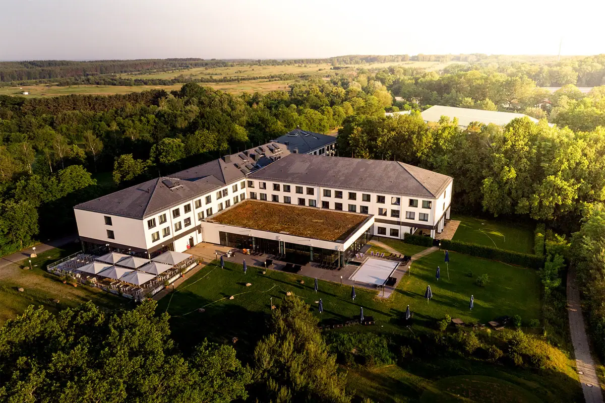 aja Bad Saarow Ein großes weißes Gebäude mit Bäumen im Hintergrund.