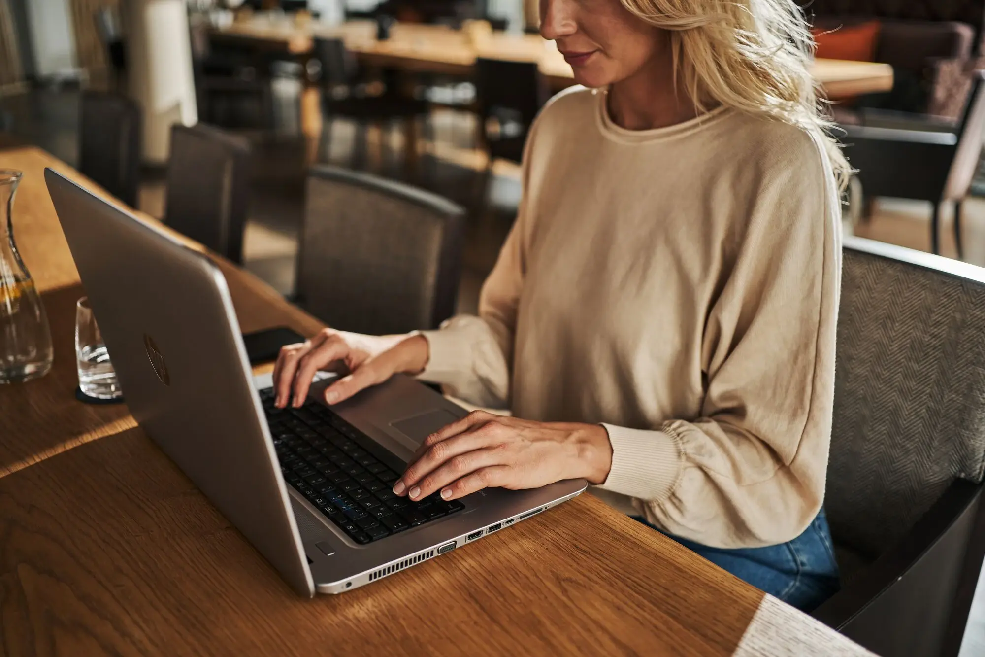 Frau sitzt an einem Tisch und benutzt einen Laptop.
