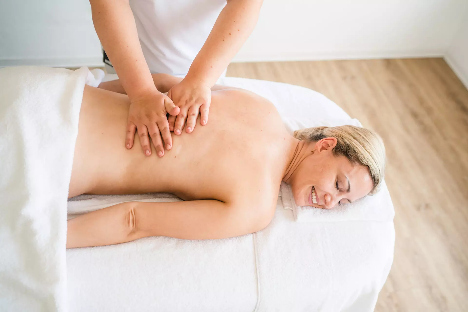 Eine Frau genießt eine entspannende Rückenmassage in einem Wellnessbereich, lächelnd und sichtlich zufrieden.