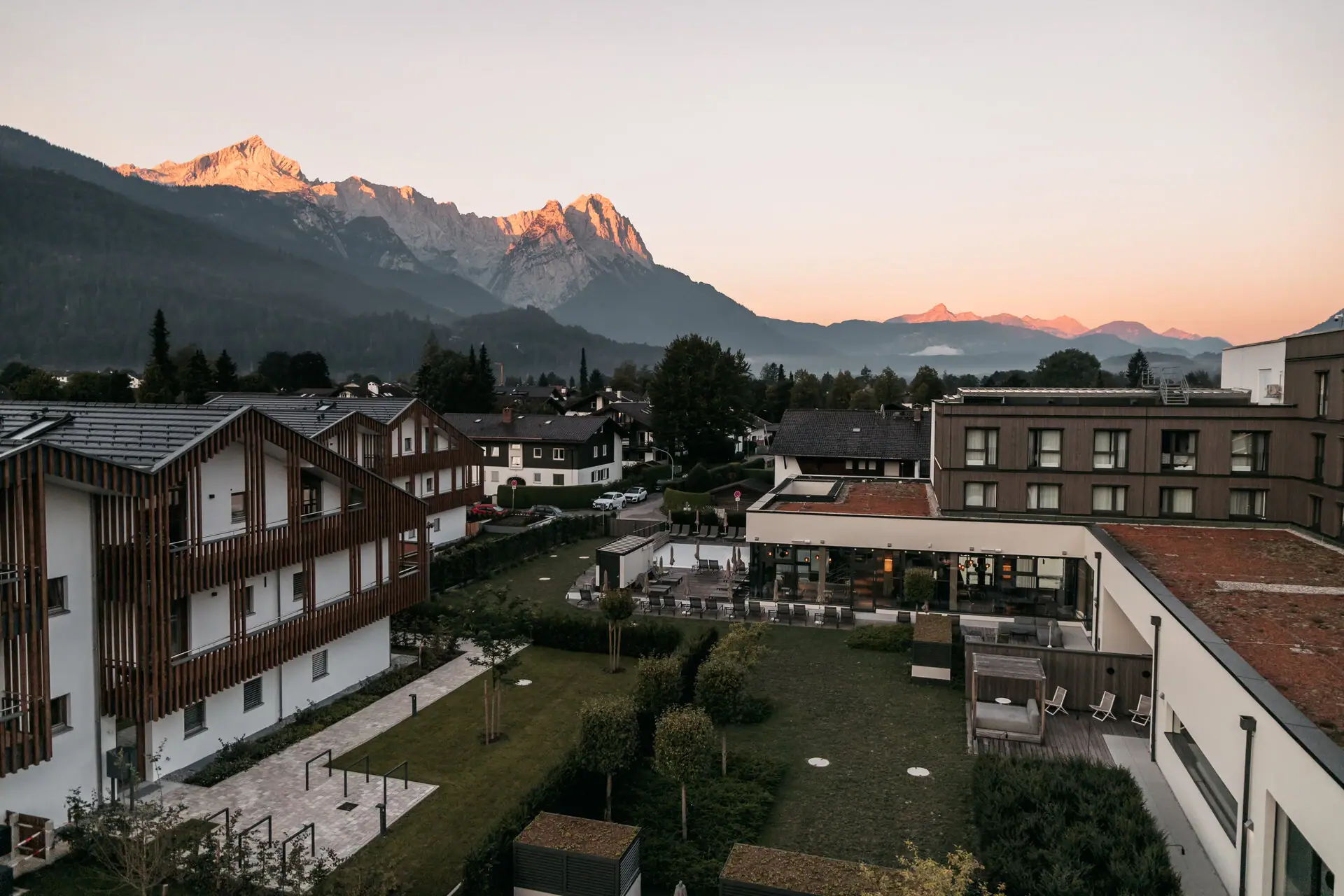 Ausblick Eine Gruppe von Gebäuden mit Bäumen und Bergen im Hintergrund.