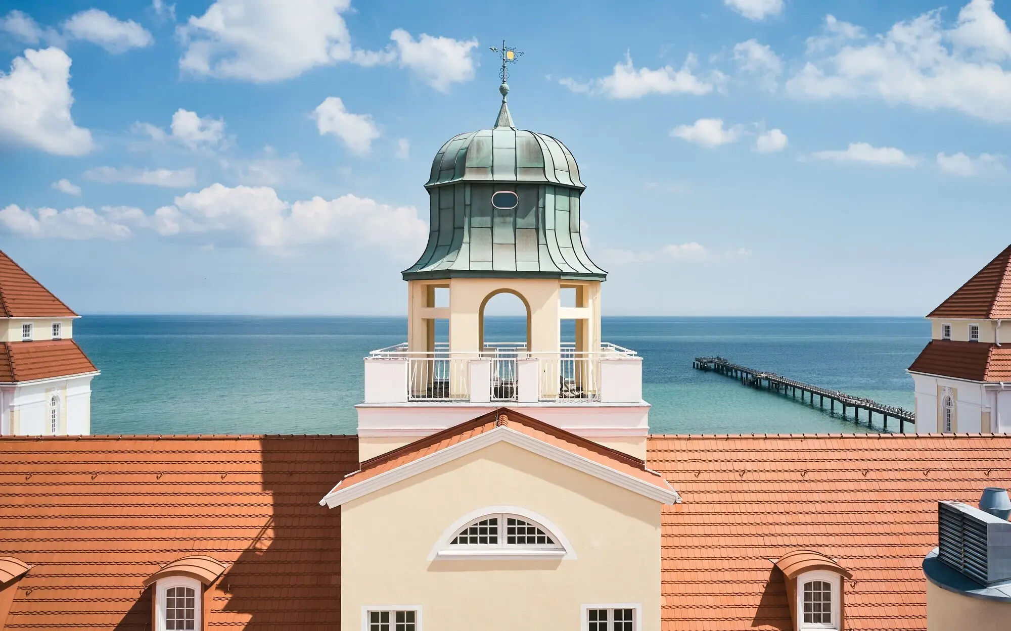 Kurhaus Binz Blick auf ein Gebäude mit einem Turm und einem Pier im Hintergrund.