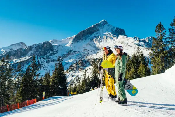 Wintersport Zwei Personen in Schneekleidung stehen auf einem verschneiten Berg.