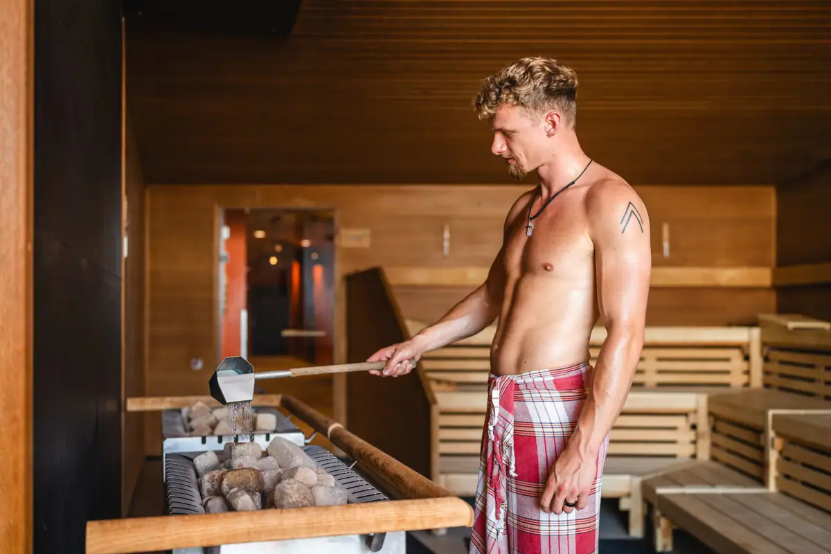 Saunaaufguss Ein Mann in rot-weiß karierten Shorts.