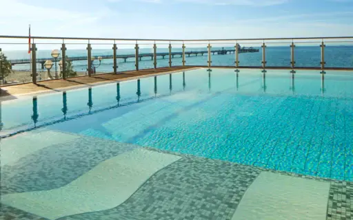 Ausblick über das ruhige Wasser des Außenpools der Grömitzer Welle auf die Ostsee im Hintergrund, welche durch eine gläserne Umzäunung vom Außenbereich des Schwimmbads abgetrennt wird. Ausblick über das ruhige Wasser des Außenpools der Grömitzer Welle auf die Ostsee im Hintergrund, welche durch eine gläserne Umzäunung vom Außenbereich des Schwimmbads abgetrennt wird.