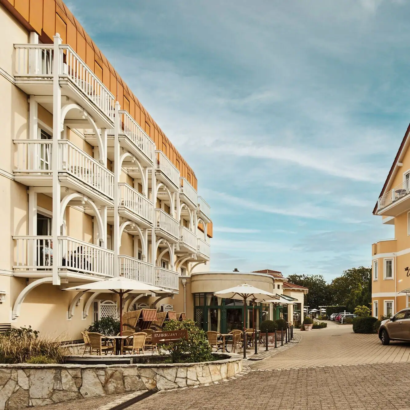 Nordperd & Villen Göhren Straße mit Gebäuden und Autos im Freien unter bewölktem Himmel.