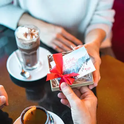 Eine Person hält eine Geschenkbox mit roter Schleife.