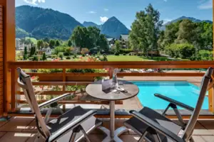 Doppelzimmer Ein Tisch und Stühle auf einem Balkon mit Blick auf einen Pool.