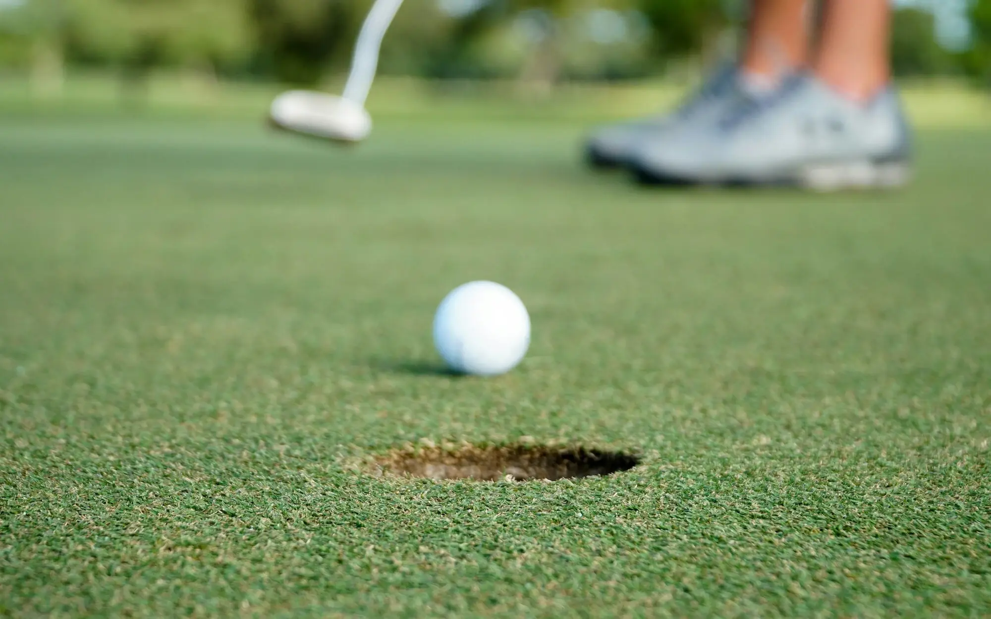 Golfball nahe einem Loch auf einem Golfplatz.