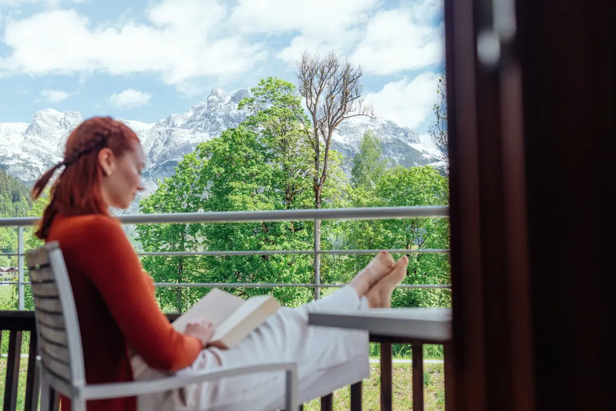 Lesen auf dem Balkon Eine Frau sitzt auf einem Balkon und liest ein Buch.
