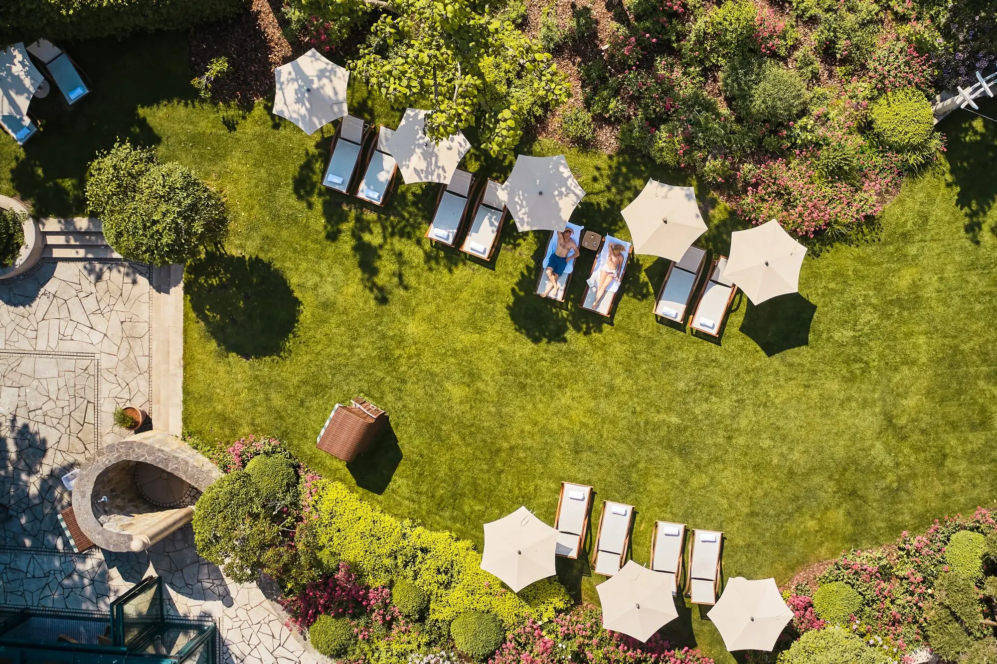 Garten im aja Bansin Gruppe von Personen sitzt auf Liegestühlen unter Sonnenschirmen in einem Garten.