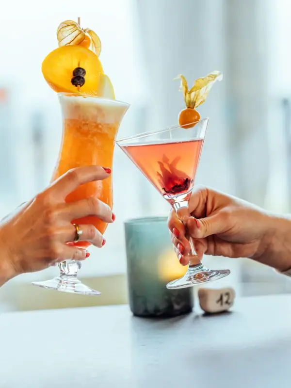 Cocktails Ein Paar Hände hält Gläser mit Getränken.