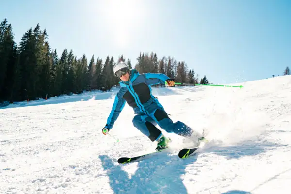 Skifahren Eine Person fährt auf Skiern einen verschneiten Hang hinunter.