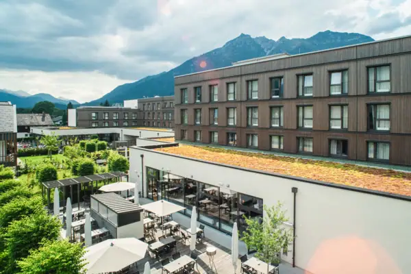 Terrasse Ein Gebäude mit Dach, Tischen und Stühlen im Freien unter bewölktem Himmel.