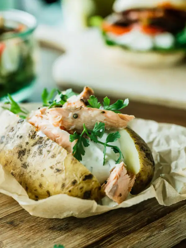 Backkartoffel Gebackene Kartoffel mit Fleisch und Grünzeug auf einem Holzbrett