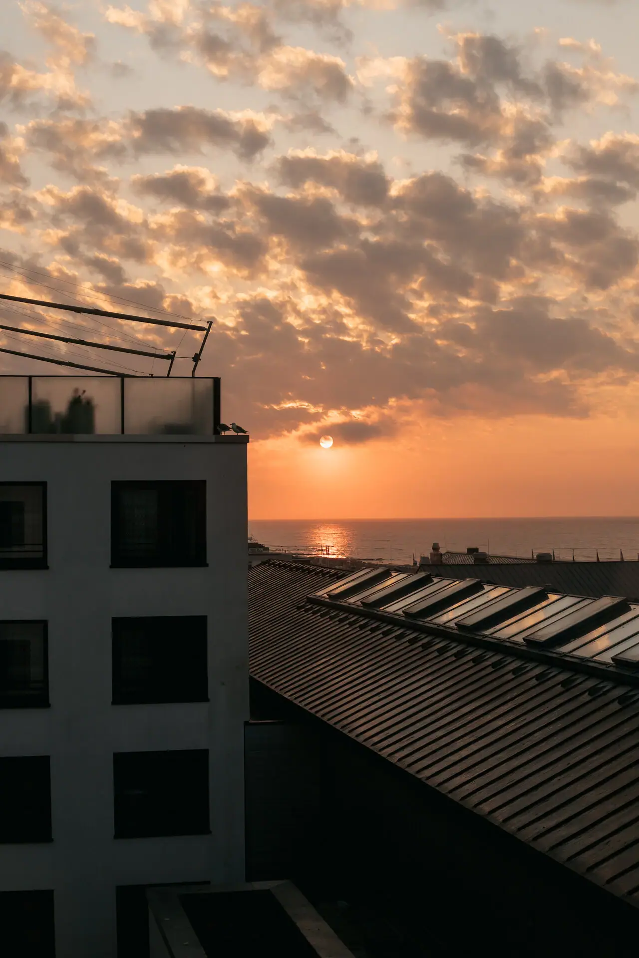 aja Grömitz Ein Gebäude mit Dach vor einem Sonnenuntergang.