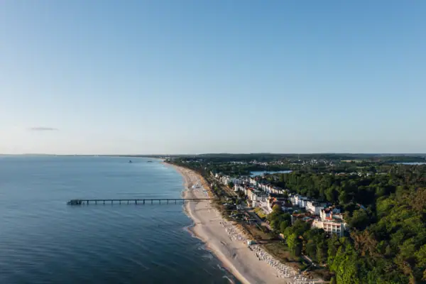 Strand mit einem Pier und Gebäuden im Hintergrund.