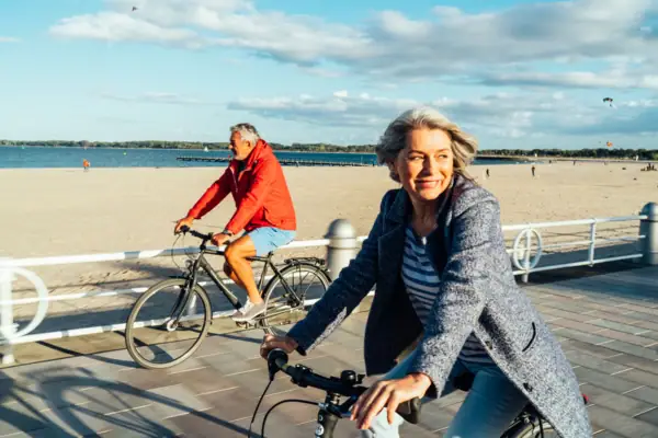 Fahrrad fahren Ein Mann und eine Frau fahren mit Fahrrädern am Strand entlang.