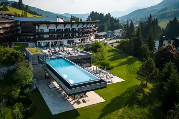 Ifen Hotel Kleinwalsertal Ein Schwimmbecken in einem Gebäude mit einem großen Gebäude und Bäumen im Hintergrund.
