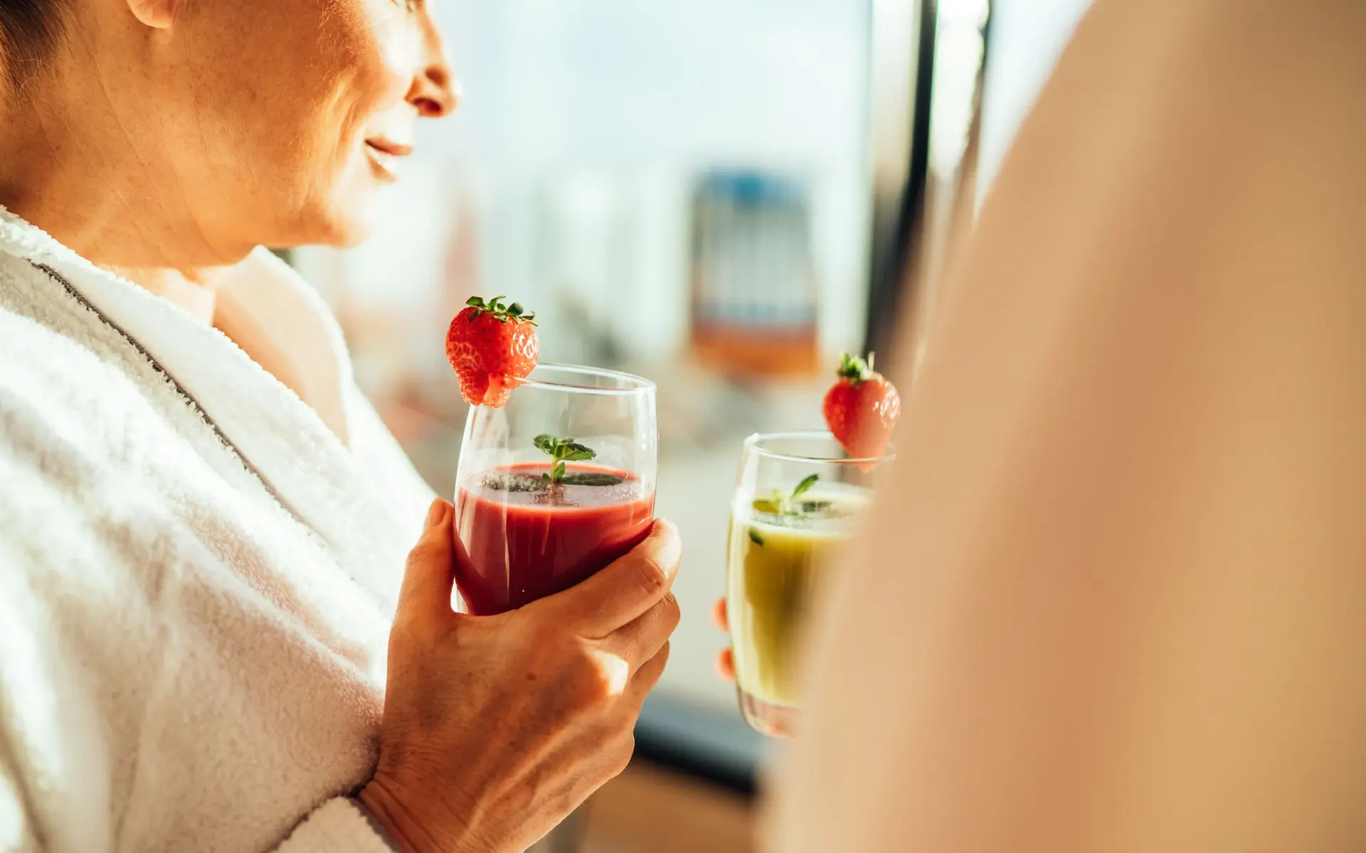 Zwei Frauen sitzen in einem SPA Bereich und trinken Smoothies.